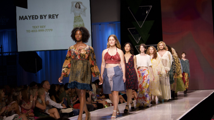 6+ individuals wearing handmade looks by ReyAnna Moore walk the runway at Omaha Fashion Week. 