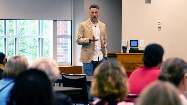 Scott Frohn holds a presentation clicker and speaks to a full room in the Nebraska Union. 