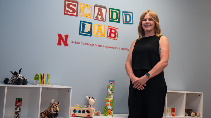 Ciara Ousley stands in front of a blue wall with colorful blocks that spell out SCADD LAB. 