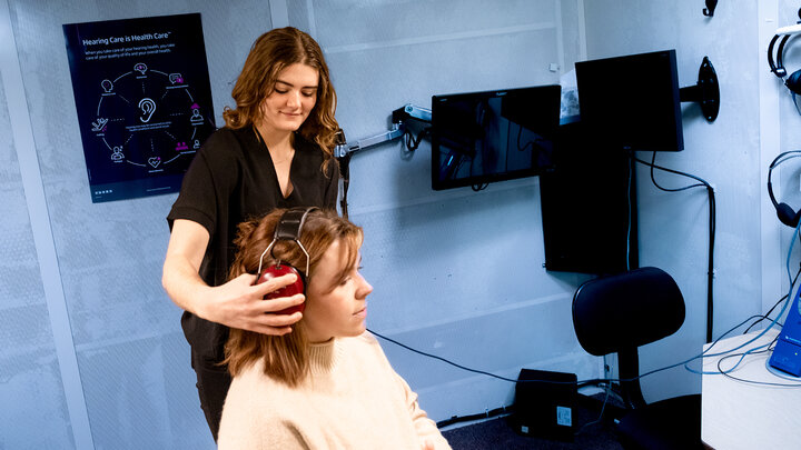 Lydia Teegerstrom places headphones on a client in a sound booth at the Barkley Speech Language and Hearing Clinic