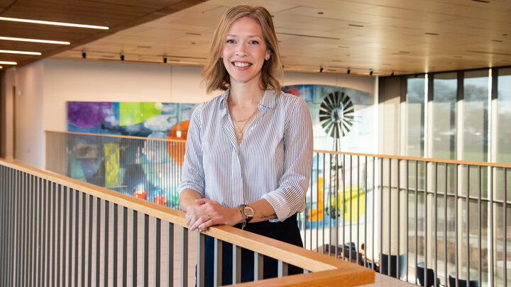 Jillian Harpster smiles for a photo on the walkway above the living room in Carolyn Pope Edwards Hall