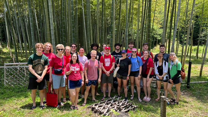 Husker students and faculty pose for a group photo in front of a bamboo forest