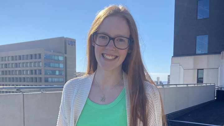 Mia Stiles smiles for a photo on a rooftop balcony