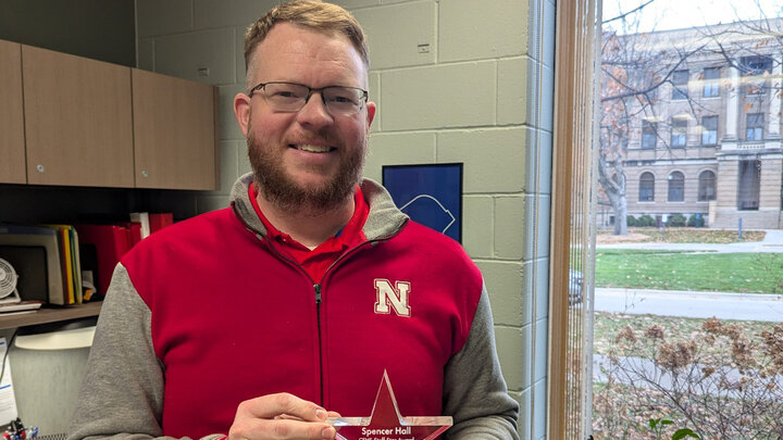 Spencer Hall holds his Staff Star Award for a photo in his office on East Campus