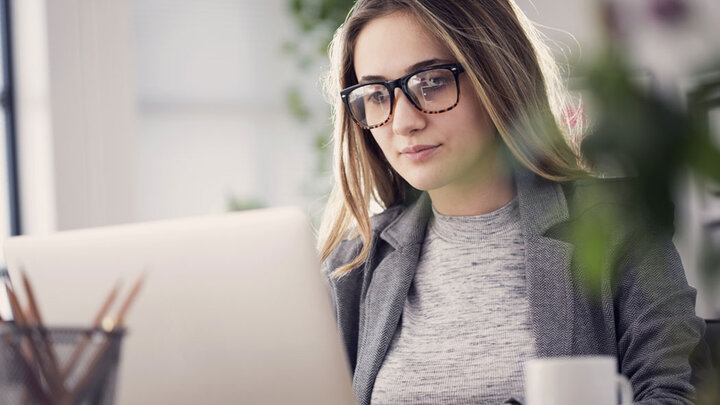 woman with glasses working on a laptop