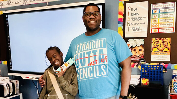 Jeremy Williams and a student smile for a photo in his classroom