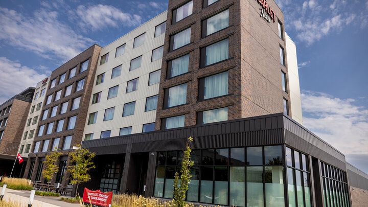 exterior of The Scarlet Hotel southwest corner with red banner outside the Hospitality, Restaurant and Tourism Management program space entrance