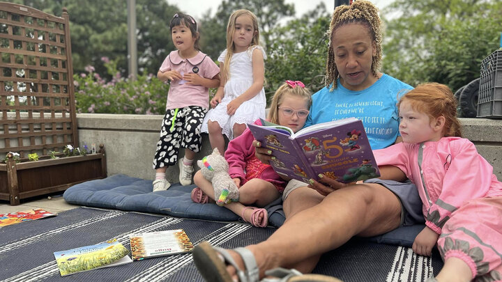 Miki Montgomery reads a book to four young children in the outdoor classroom at the Ruth Staples Child Development Lab.