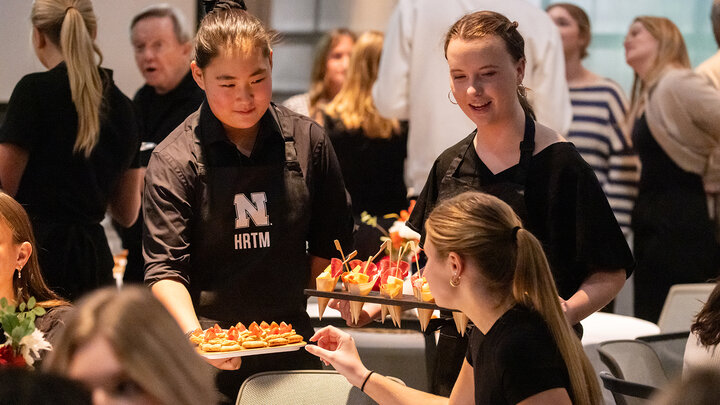 two HRTM students serve hors d'oeuvres to guests at the UNLimited Hospitality event in 2024