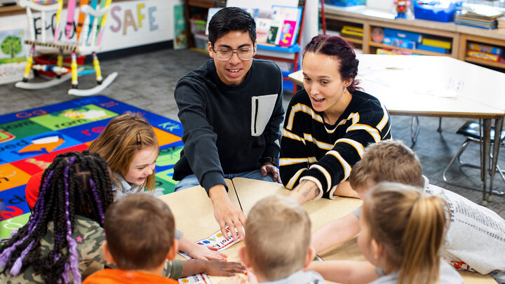Carlos Ortega and another student work with a group of young children at a table in a classroom
