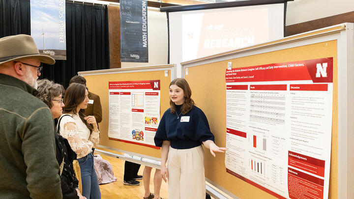Grace Fowler presents her research poster to a group of people at Nebraska Student Research Days in Spring 2026