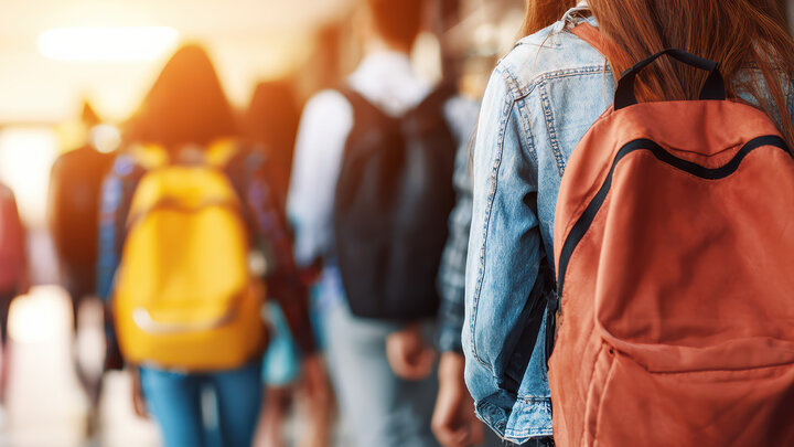 female student with orange backpack in school hallway