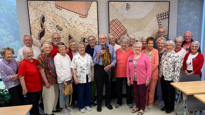 Eastmont Towers residents pose for an image with Dr. Robert Hillestad in the center holding a piece of art.