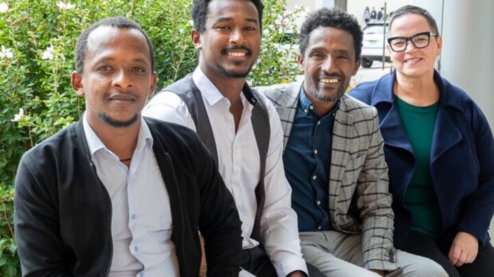 Four individuals sitting outdoors posing for a photo. 