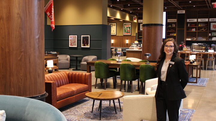 Rebecca Ellers stands in The Scarlet Hotel lobby which is filled with rich woods, and leather furniture.