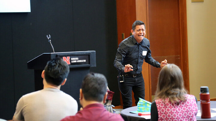 HÃ©ctor Palala presents at the front of the room near a podium during the Student Research Slam. 