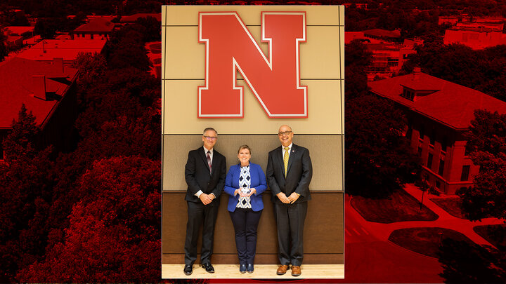 Three individuals dressed in professional attire posing for a photo. 