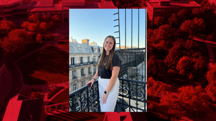 Lauren Mortenson stands on a balcony outdoors, with large ornate buildings behind her. That photo is placed on a red graphic. 