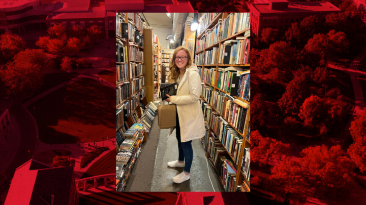 Photo of Presley Pribil standing in-between rows of bookcases. Placed on a red background. 