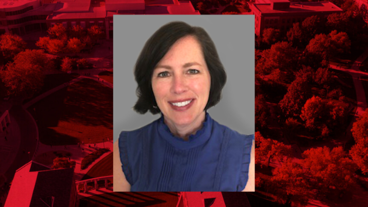 Professional headshot of Tina Horan on a red background. 