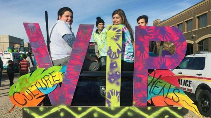 Youth on a parade float next to large colorful letters that read VIP. 