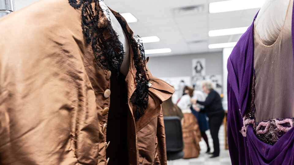 Textiles on mannequins with students and staff in background.