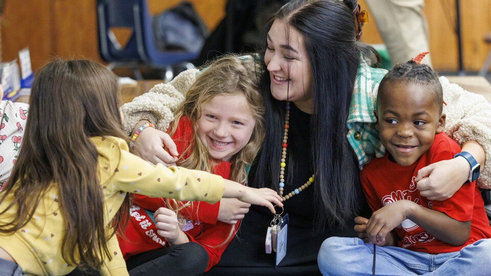 Woman hugging some kids on floor.