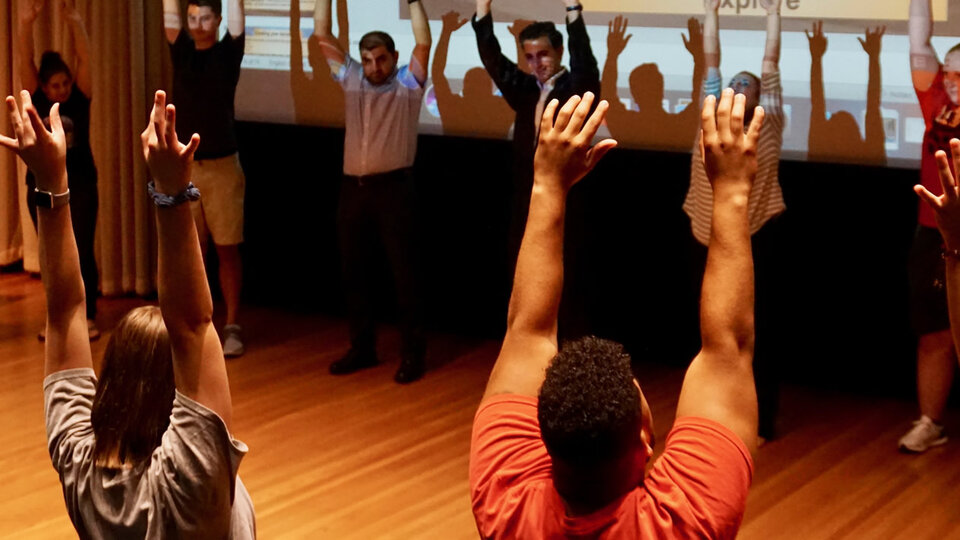 People in group raising hands in ritual fashion.