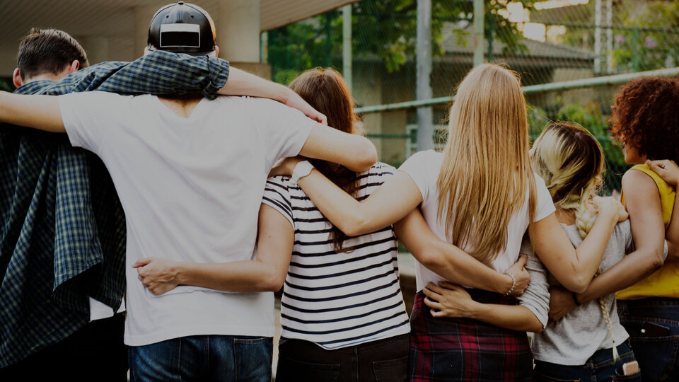 Group of people facing away with arms interlocked.