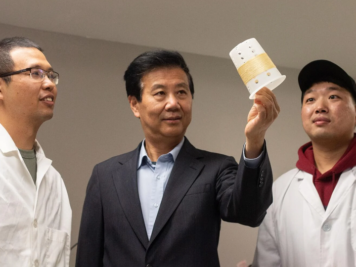 Yiqi Yang (center) holds a cylinder of fibers to observe with a student on each side of him
