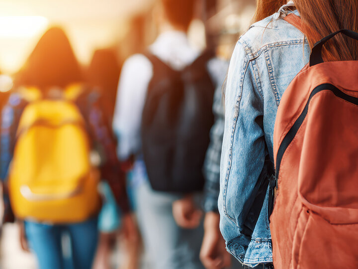 female student with orange backpack in school hallway
