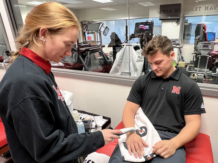 Person using a handheld device to check another’s hand in a sports clinic.