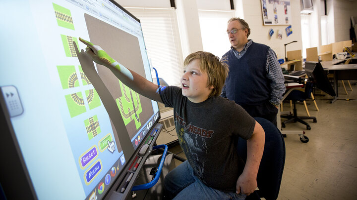 Child working on giant touch screen.