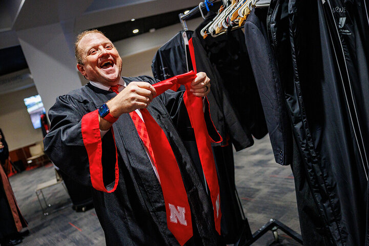 Svehla shares a laugh as he puts his Nebraska sash over his graduation gown.