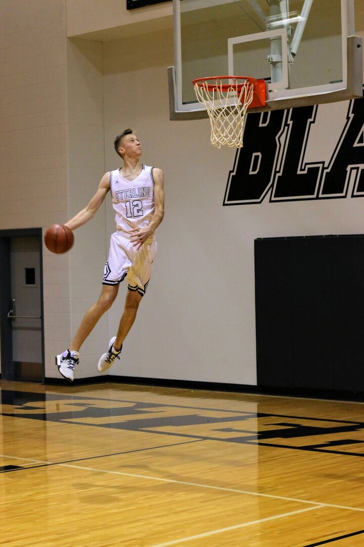 Tyus Wilson goes up for a dunk while playing basketball at his high school.