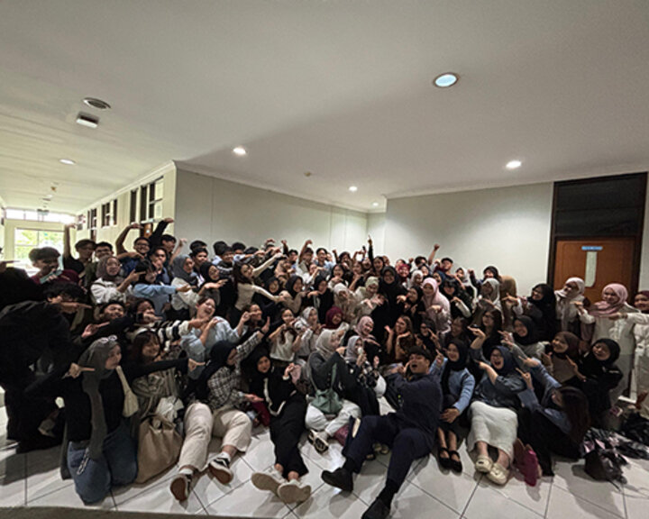 Theresa Catalano sits amid a large group of students from Universitas Pendidikan Indonesia (UPI) pointing to her for a group photo.
