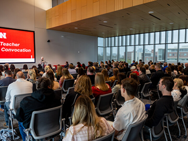 Marjorie Kostelnik provides the keynote address to a room full of people seated in rows of chairs with a wall of windows on one side of the room during the Teacher Education Convocation in Carolyn Pope Edwards Hall.