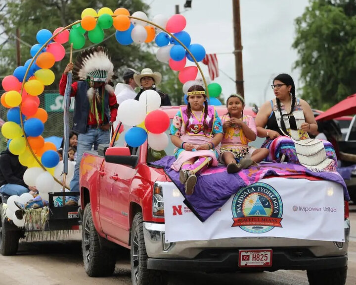 Kids riding on a car during parade.