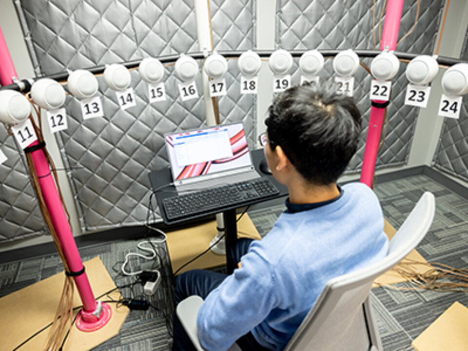 a student sits in a room conducting audiology research