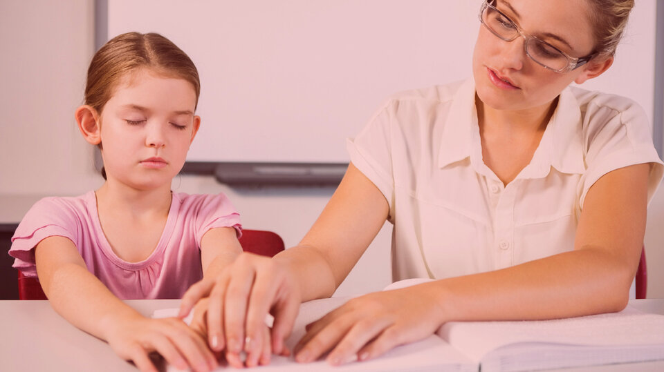 Woman helping girl with brail.