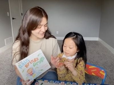 Woman reading book to small girl.