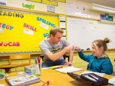 Teacher fist bumping a student in classroom.