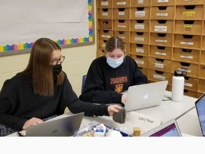 Two students working on their computers in classroom.