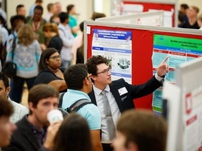 Group of students looking at board during a poster session.