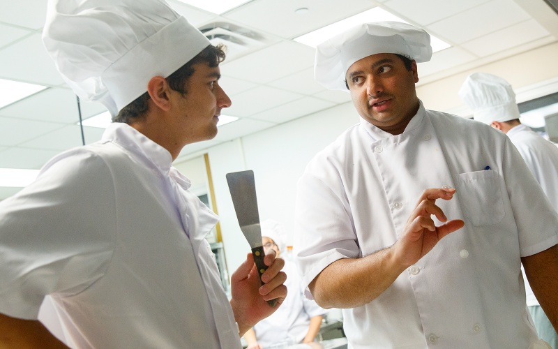 Two students dressed as chefs having a discussion.