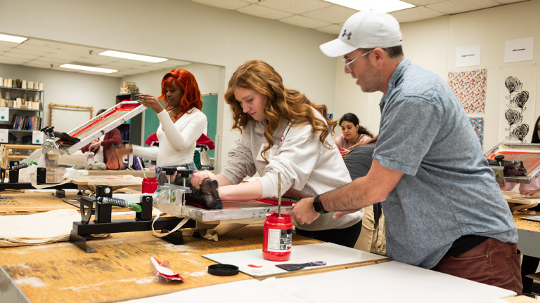 Michael Burton, assistant professor of art and design, assists a visiting high school student with a screen printing project during the TMFD Expo.