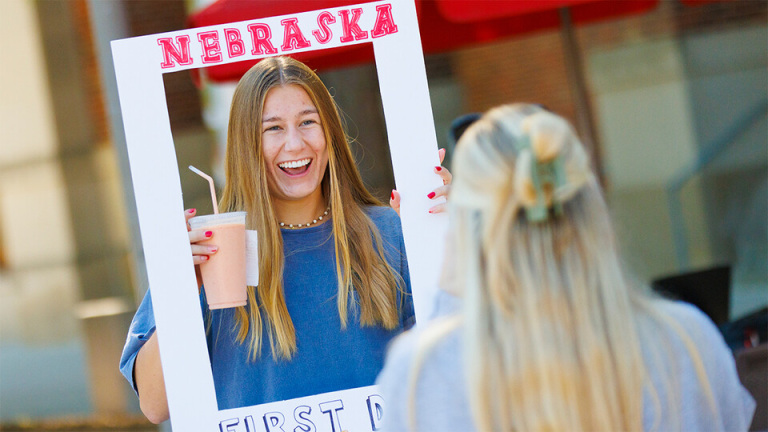 One person wearing a blue shirt holds a smoothing an a photo frame that says "NEBRASKA"